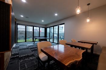 a conference room with a wooden table and chairs and large windows at 310 at Nulu Apartments-Student, Louisville, KY
